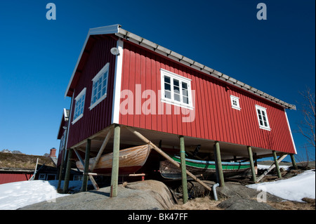 Traditional red wooden Rorbu fisherman`s hut with fishing boats stored below in village of Reine in Lofoten Islands in Norway